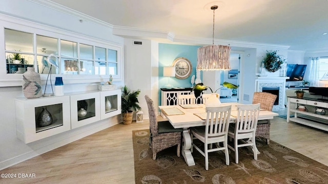 dining room with hardwood / wood-style floors, a fireplace, and ornamental molding