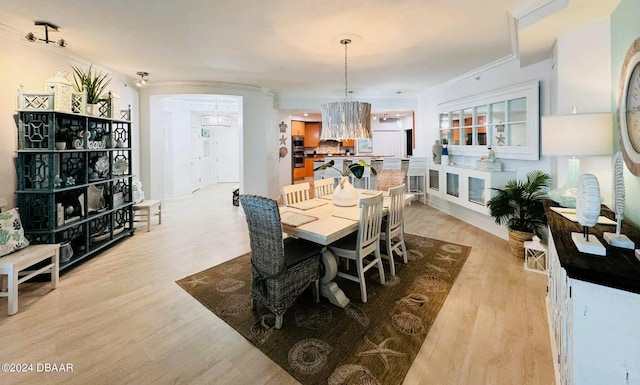 dining area with light hardwood / wood-style floors, crown molding, and an inviting chandelier