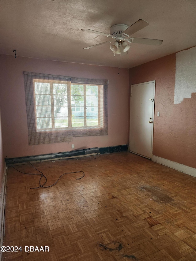 spare room featuring parquet flooring, a textured ceiling, ceiling fan, and plenty of natural light