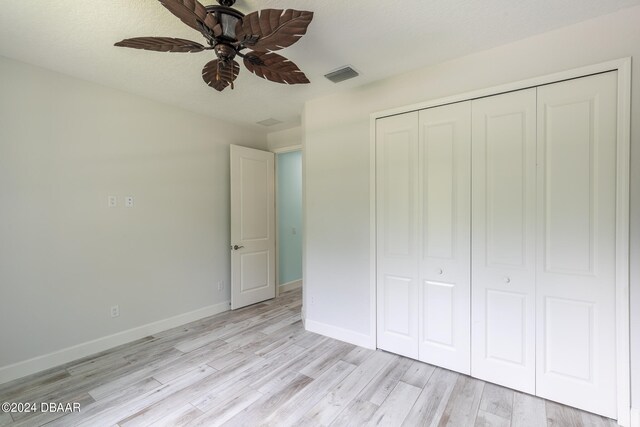 unfurnished bedroom featuring a textured ceiling, light hardwood / wood-style floors, ceiling fan, and a closet