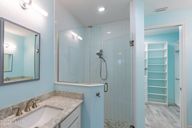 bathroom featuring walk in shower, hardwood / wood-style floors, and vanity