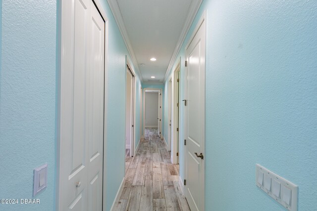 hall with ornamental molding and light wood-type flooring