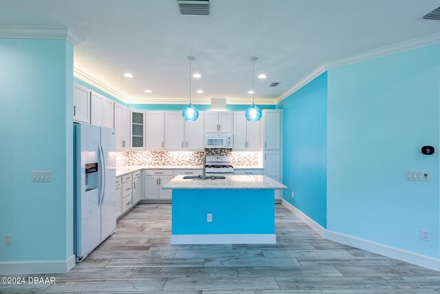 kitchen with a center island with sink, white appliances, crown molding, white cabinets, and pendant lighting