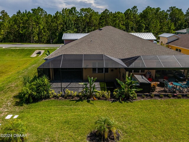 back of property with glass enclosure and a yard