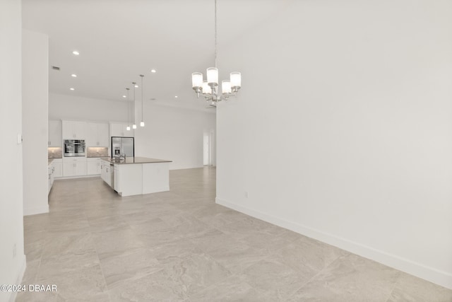 kitchen with appliances with stainless steel finishes, a kitchen island with sink, an inviting chandelier, white cabinets, and decorative light fixtures