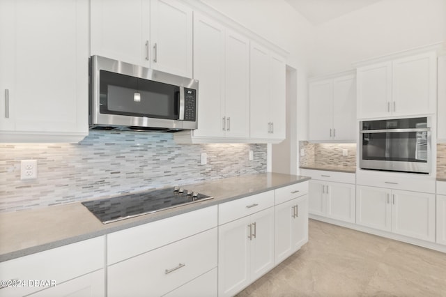 kitchen featuring white cabinets, stainless steel appliances, decorative backsplash, and light countertops