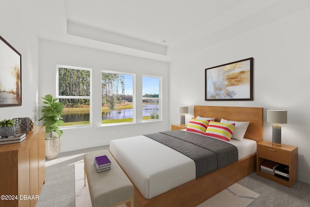 bedroom featuring light carpet, a tray ceiling, and a water view