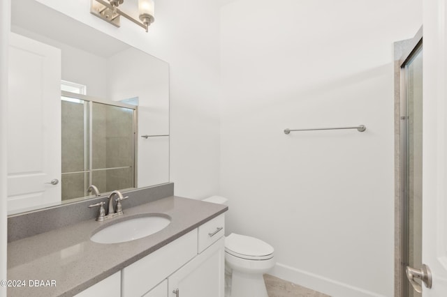 bathroom with toilet, vanity, and a shower with shower door