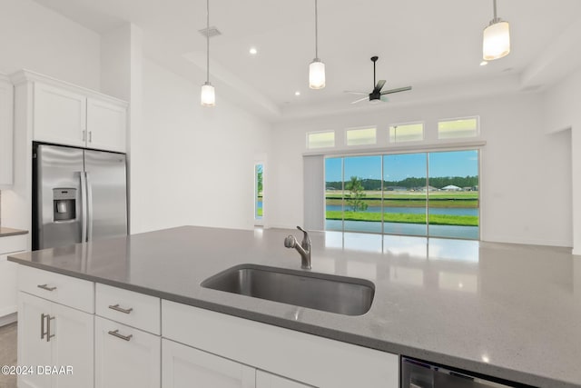 kitchen with white cabinets, dark stone counters, decorative light fixtures, stainless steel appliances, and a sink