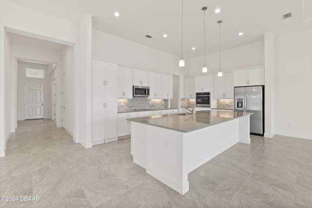 kitchen featuring sink, white cabinetry, hanging light fixtures, stainless steel appliances, and a kitchen island with sink