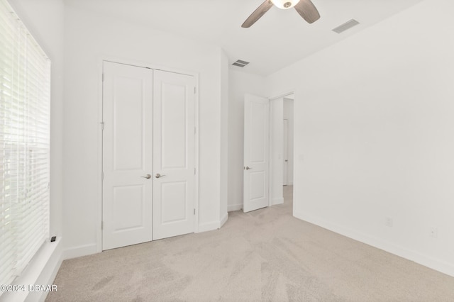 unfurnished bedroom with ceiling fan, a closet, and light carpet