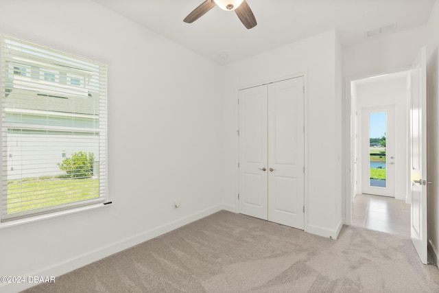 unfurnished bedroom with carpet floors, a closet, baseboards, and a ceiling fan