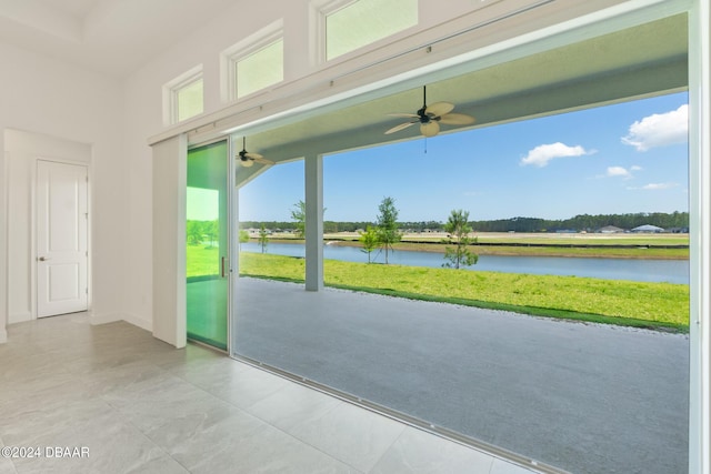 doorway to outside with a water view, ceiling fan, and baseboards