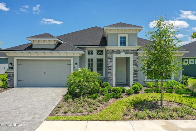 view of front of house with a garage, stone siding, decorative driveway, and stucco siding