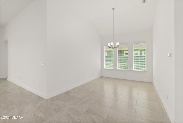 spare room with a chandelier, vaulted ceiling, and baseboards