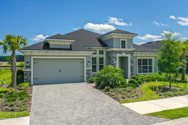 view of front of home with a garage, stone siding, roof with shingles, decorative driveway, and stucco siding