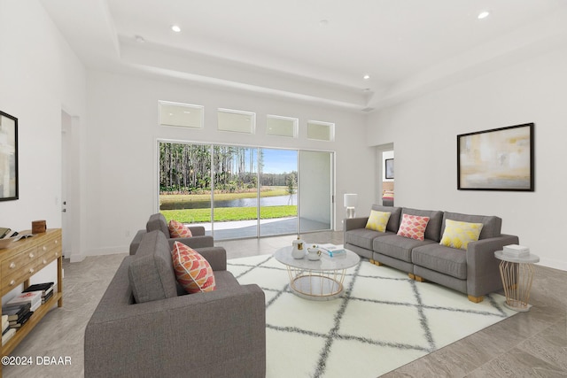 living room featuring recessed lighting, a raised ceiling, a towering ceiling, and baseboards