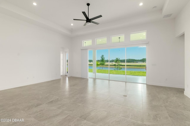 spare room featuring recessed lighting, a water view, a high ceiling, a ceiling fan, and baseboards