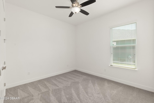 carpeted empty room featuring a ceiling fan and baseboards