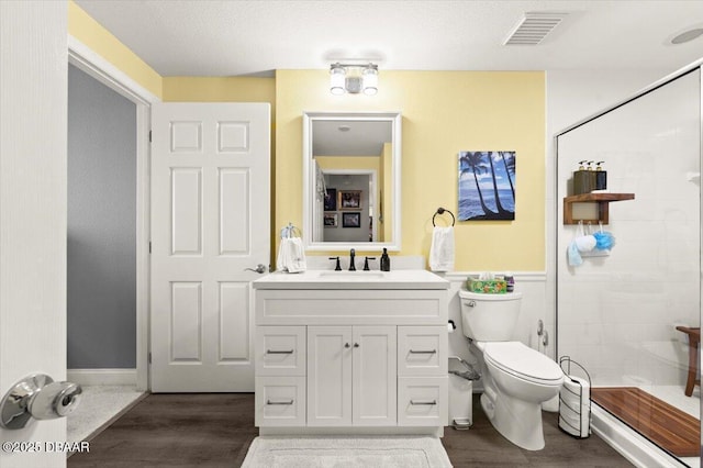 bathroom featuring wood finished floors, visible vents, toilet, and a stall shower