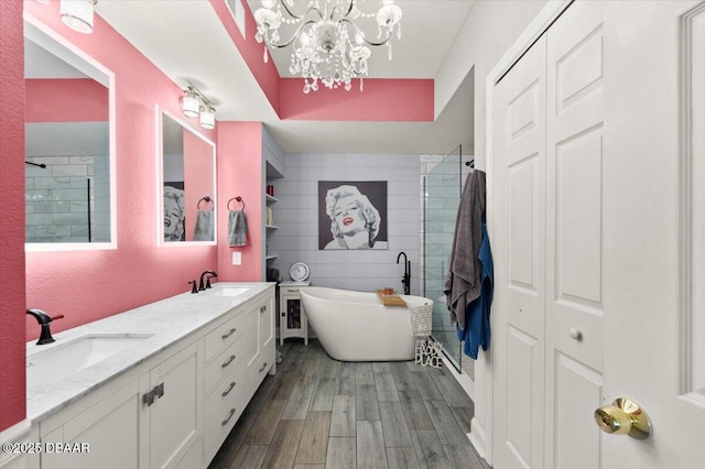 bathroom with a sink, a shower stall, a freestanding tub, double vanity, and wood finished floors