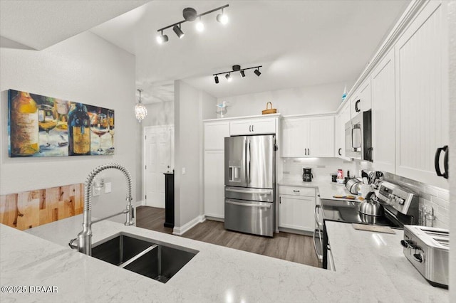 kitchen featuring appliances with stainless steel finishes, decorative backsplash, light stone countertops, and a sink
