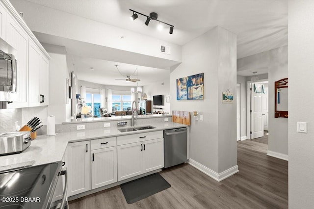 kitchen with appliances with stainless steel finishes, white cabinets, dark wood finished floors, and a sink
