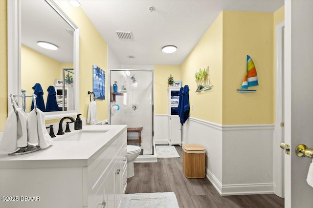 full bathroom featuring wood finished floors, vanity, baseboards, visible vents, and a stall shower