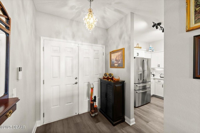 entryway featuring an inviting chandelier, wood finished floors, and baseboards