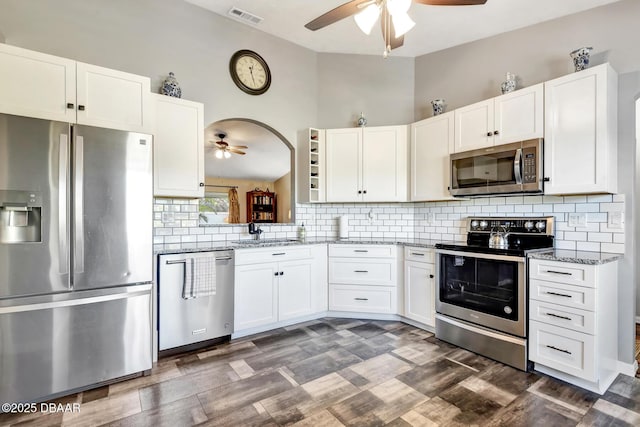 kitchen with white cabinets, stainless steel appliances, light stone counters, and sink