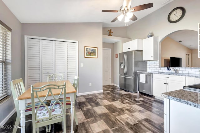 kitchen with dark wood-type flooring, stainless steel appliances, backsplash, vaulted ceiling, and white cabinets