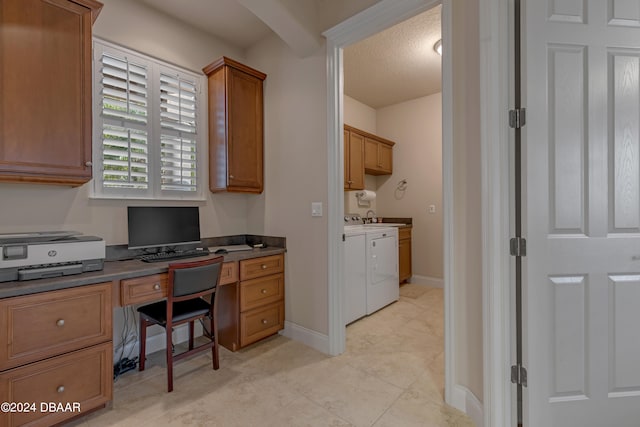 office area with built in desk, washer and dryer, and a textured ceiling