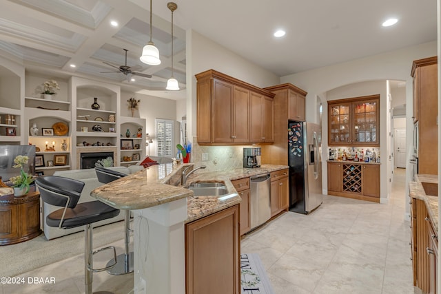 kitchen featuring a kitchen bar, stainless steel appliances, kitchen peninsula, sink, and decorative light fixtures