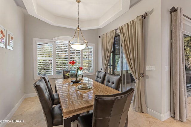 tiled dining space with a tray ceiling