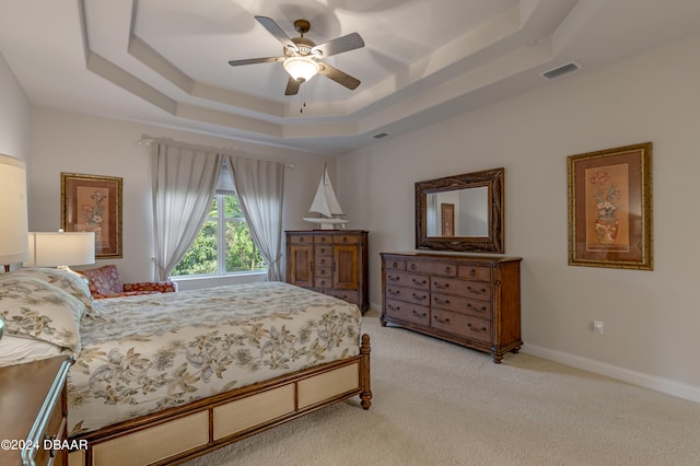 bedroom with ceiling fan, light carpet, and a raised ceiling