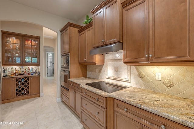 kitchen with appliances with stainless steel finishes, tasteful backsplash, light tile patterned flooring, and light stone counters