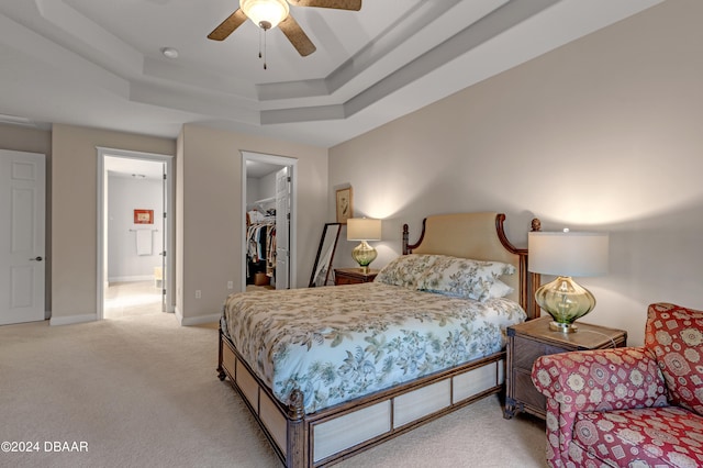 carpeted bedroom featuring a closet, a walk in closet, ceiling fan, and a raised ceiling