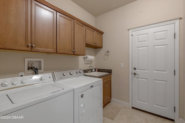 washroom with cabinets, light tile patterned flooring, sink, a textured ceiling, and washing machine and dryer