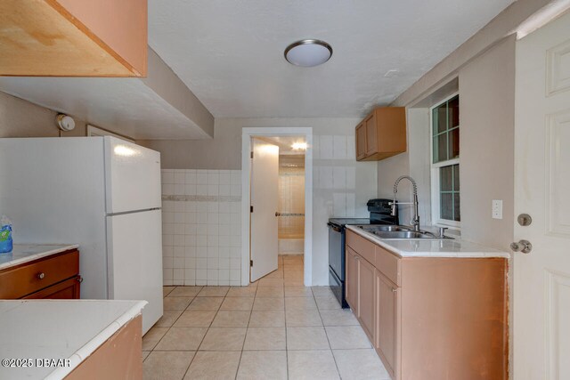 634 Aberdeen St, Daytona Beach, FL 32114 - kitchen with a sink, black range with electric cooktop, freestanding refrigerator, light tile patterned floors, and light countertops