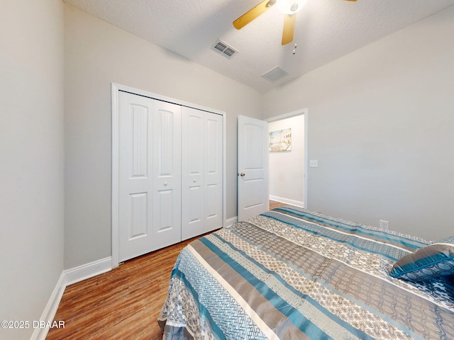 bedroom featuring ceiling fan, a closet, a textured ceiling, and wood-type flooring