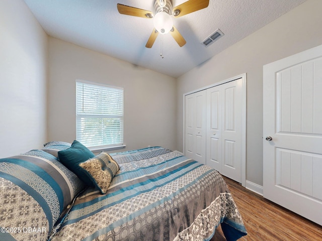 bedroom featuring ceiling fan, hardwood / wood-style floors, a closet, and a textured ceiling