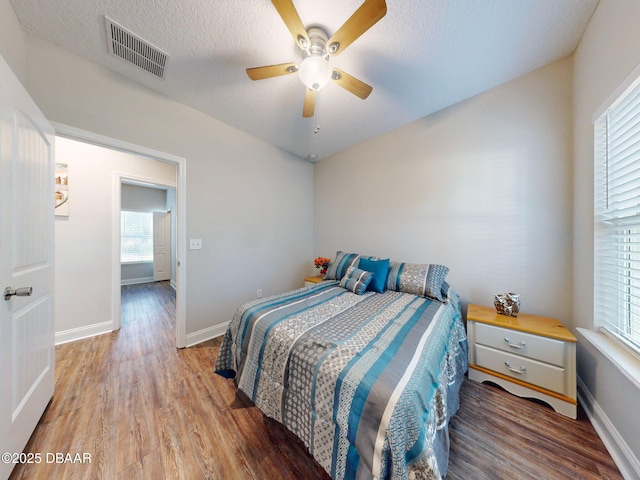 bedroom with a textured ceiling, ceiling fan, and hardwood / wood-style floors