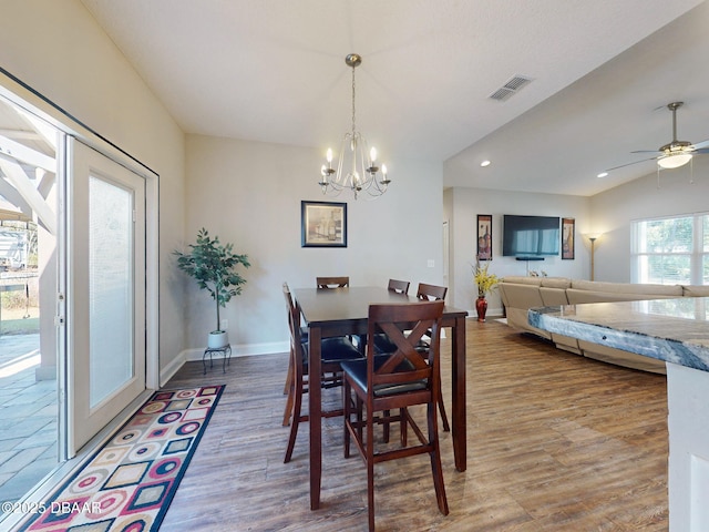 dining space with wood-type flooring and ceiling fan with notable chandelier