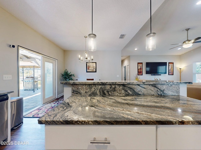 kitchen featuring a textured ceiling, wood-type flooring, dark stone counters, and decorative light fixtures