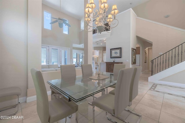 dining area with ceiling fan with notable chandelier, light tile patterned floors, and a towering ceiling