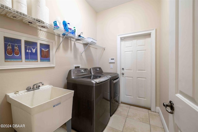 washroom with sink, independent washer and dryer, and light tile patterned floors