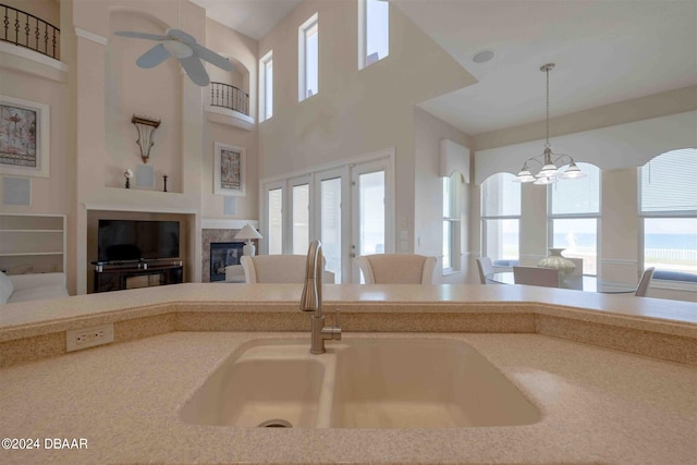 kitchen with a high ceiling, ceiling fan with notable chandelier, sink, and decorative light fixtures