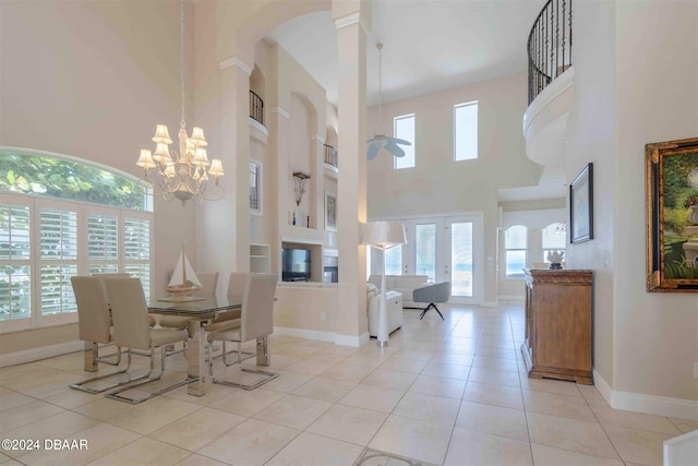 tiled dining room featuring a high ceiling and ceiling fan with notable chandelier