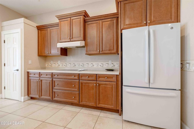 kitchen featuring cooktop, light tile patterned floors, and white fridge