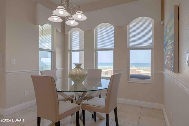 dining space featuring a water view, a notable chandelier, and light tile patterned flooring